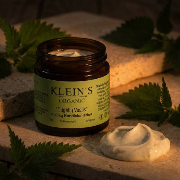 Jar of Klein's Organic product with green leaves and cream on a stone surface
