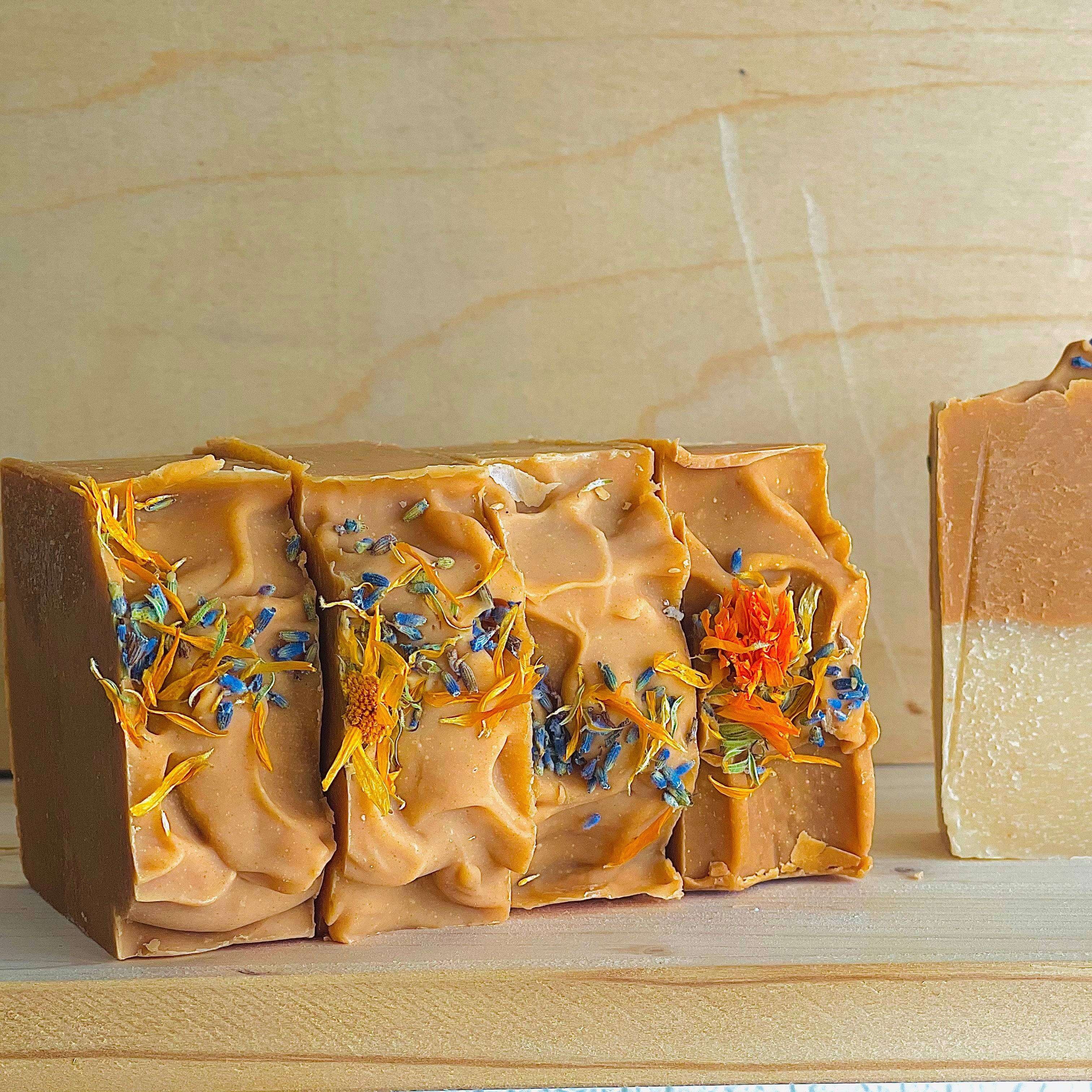 Three bars of soap with natural ingredients on a wooden surface
